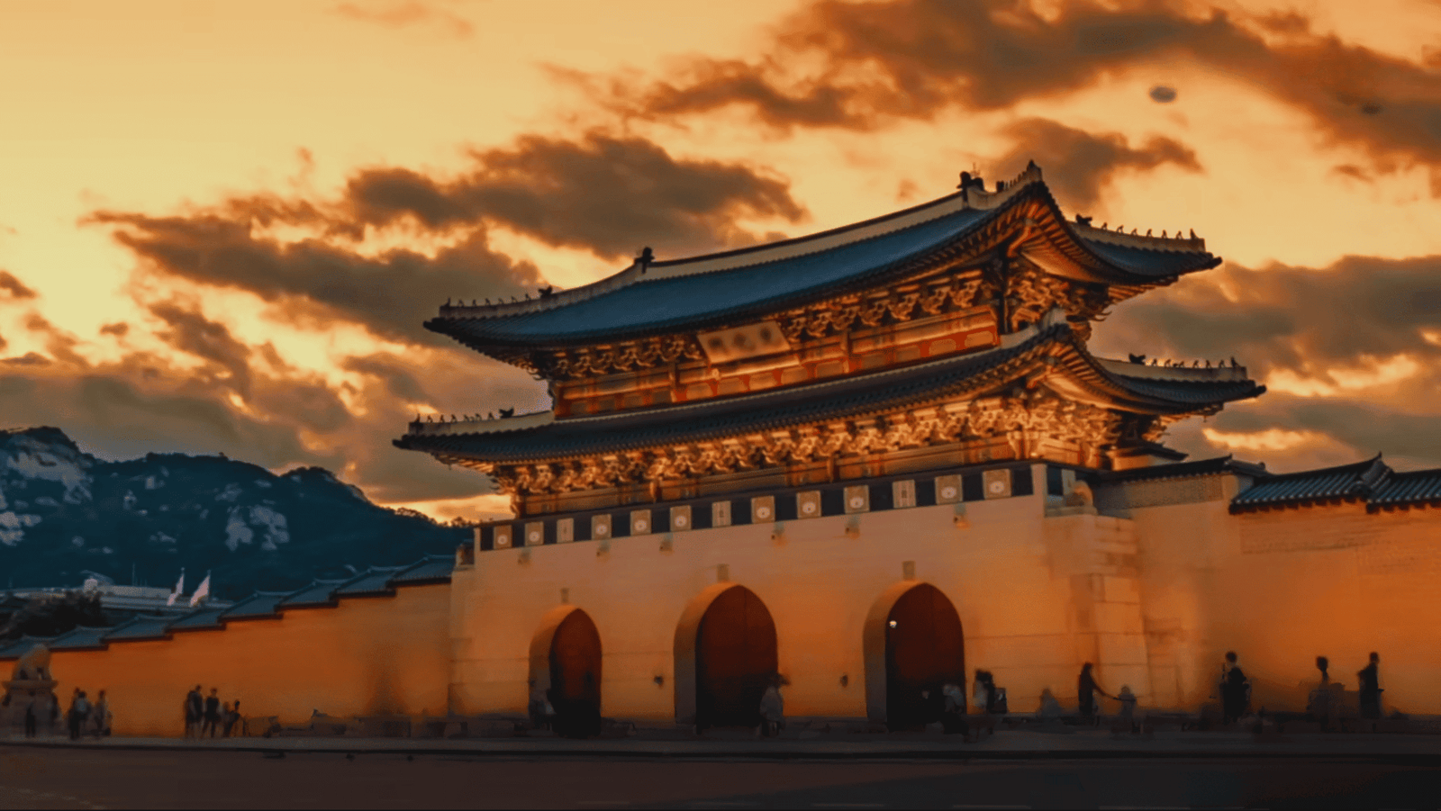 Porte traditionnelle coréenne illuminée au coucher du soleil, avec un ciel orangé et nuageux en arrière-plan